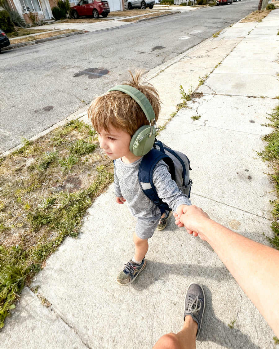 A boy in kalmkind ear defenders on the walk to school